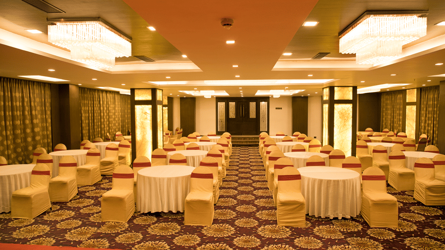 A banquet hall at Benzz Park Chennai set up with round tables and chairs with white covers, ready for an event.