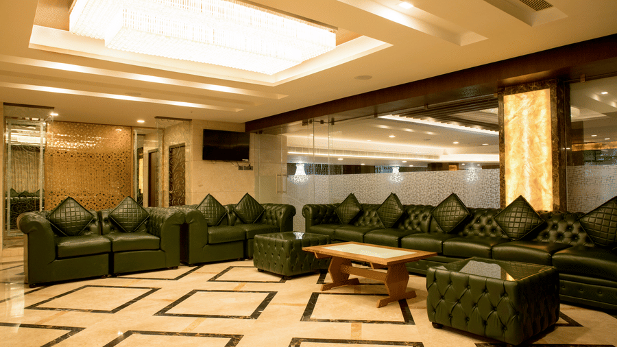 A spacious lounge area at Benzz Park Chennai with dark green sofas and a patterned floor, ideal for relaxation.