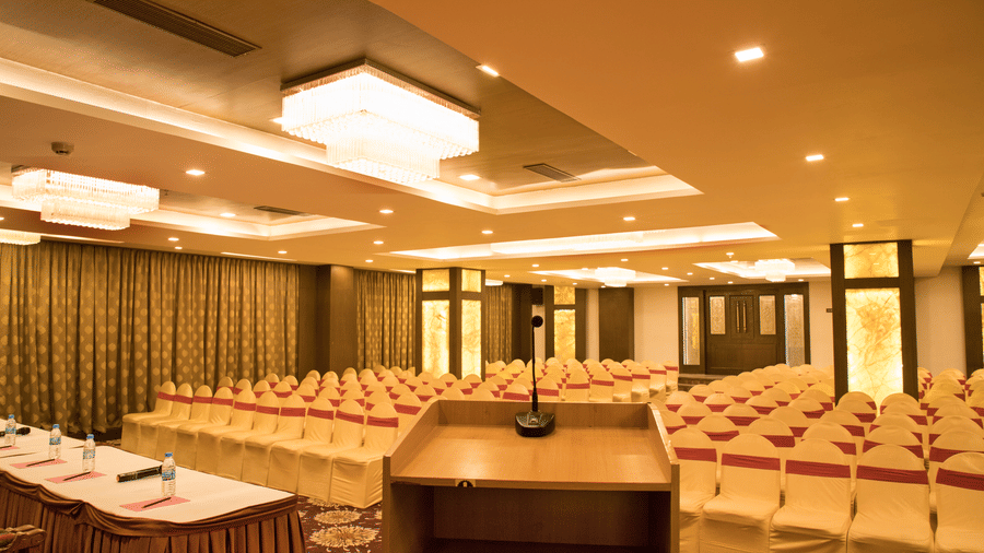 A conference room at Benzz Park Chennai set up with rows of tables and chairs, facing a podium.