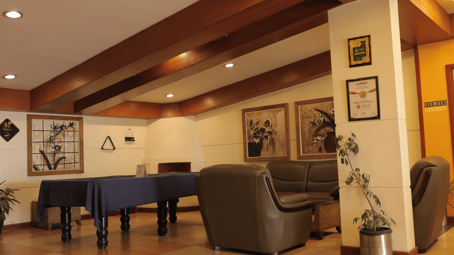 A leisure area featuring a billiard table, comfortable armchairs, and framed artwork, all beneath exposed wooden beams - Benzz Park, Kodaikanal