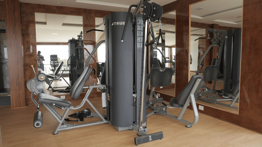 A well-equipped gym with various exercise machines and mirrored walls - Benzz Park, Kodaikanal