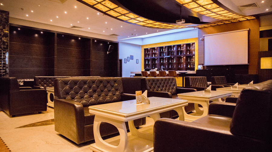 Full view of the dining area at the Benzz Park, Vellore, with warm lighting featuring tufted couch.
