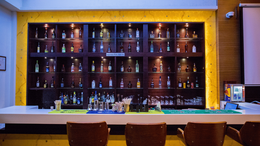 Front view shot of the bar area with an assortment of premium liquor bottles on display behind the bar counter at Benzz Park, Vellore.