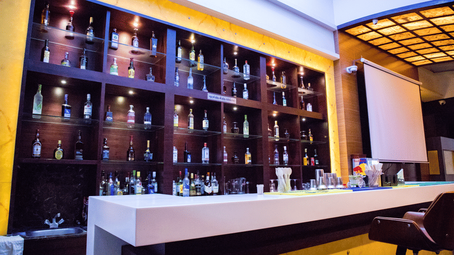 Side view of the bar featuring the bar counter and a display cabinet stacked with various liquor bottles on display at Benzz Park, Vellore.
