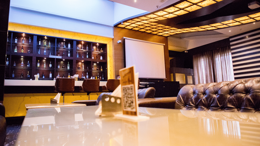 The bar at the Benzz Park, Vellore, taken from the dining table in the restaurant showcasing various liquor bottles on display behind the bar counter.