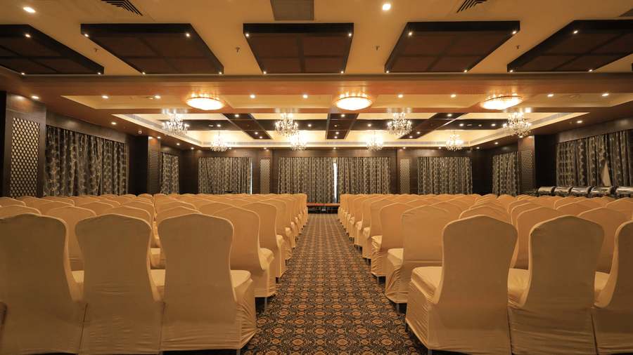 Full view of the Rolse Royse banquet hall with chairs facing towards the stage with a pathway in the middle at Benzz Park, Vellore.