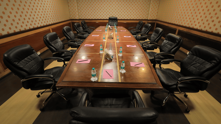 The boardroom at Benzz Park, Vellore featuring a wooden conference table lined with black cushioned office chairs.
