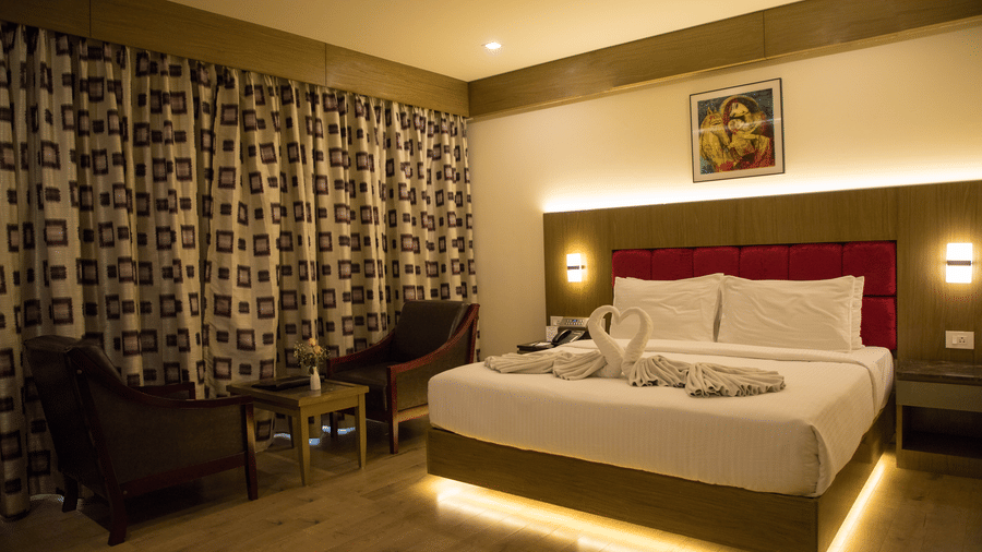 Full view of the Deluxe Room at the Benzz Park, Vellore, featuring a double bed with under-bed lights alongside a common seating area.