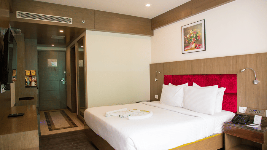Side view of the Deluxe Room with ample of natural light coming inside featuring a double bed along with the entrance to the room at the Benzz Park, Vellore.