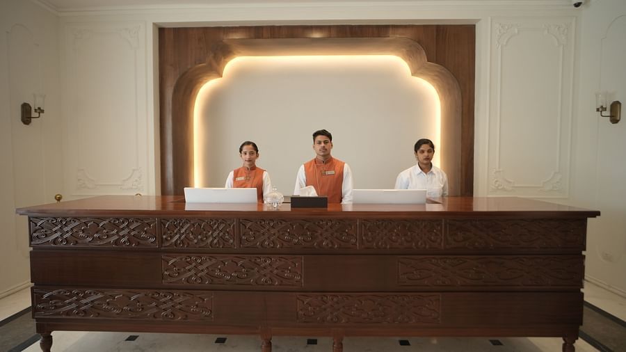 Three staff members standing behind the reception desk at Bhagirathi by RDB Atishay.