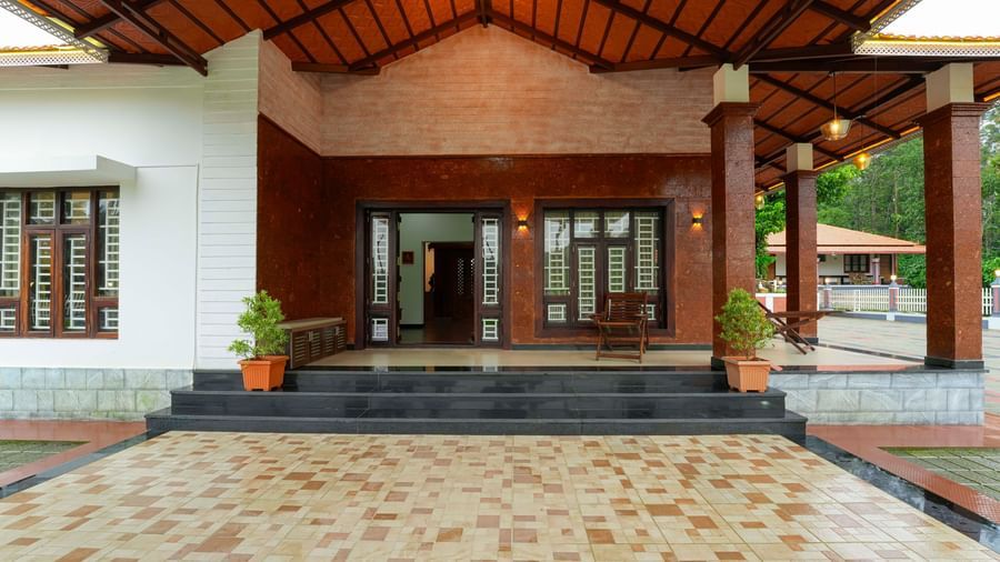 A straight-on shot of the main building at Bhuthanakadu Retreat, showing the entrance with its steps and a large, welcoming doorway, with the courtyard in the foreground.