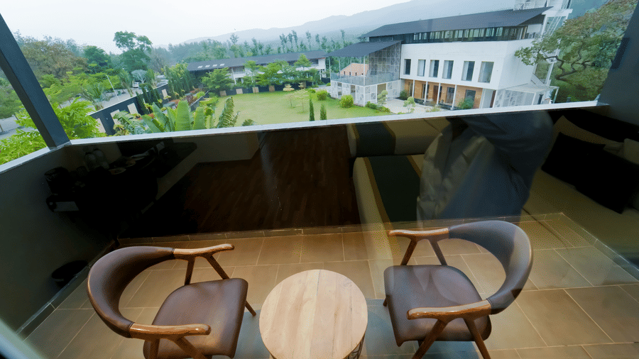 A balcony at Bindiga Peak Resort with 2 chairs and a small round table.