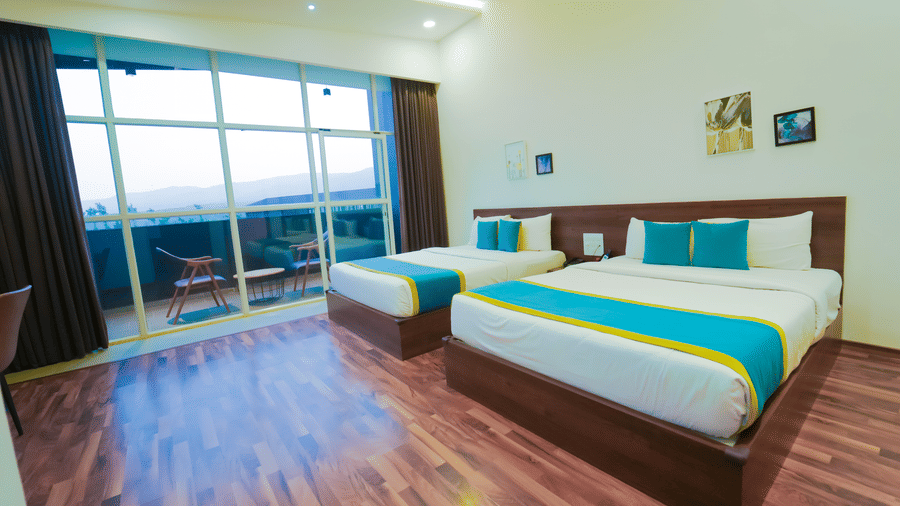 Executive Suite at Bindiga Peak Resort with wooden flooring, 2 large beds with pillows, and a glass door leading to the balcony.