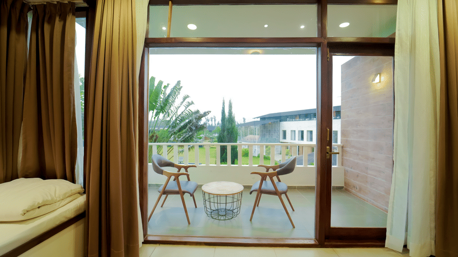 A room at Bindiga Peak Resort featuring brown curtains and glass door leading to the balcony with a seating area.