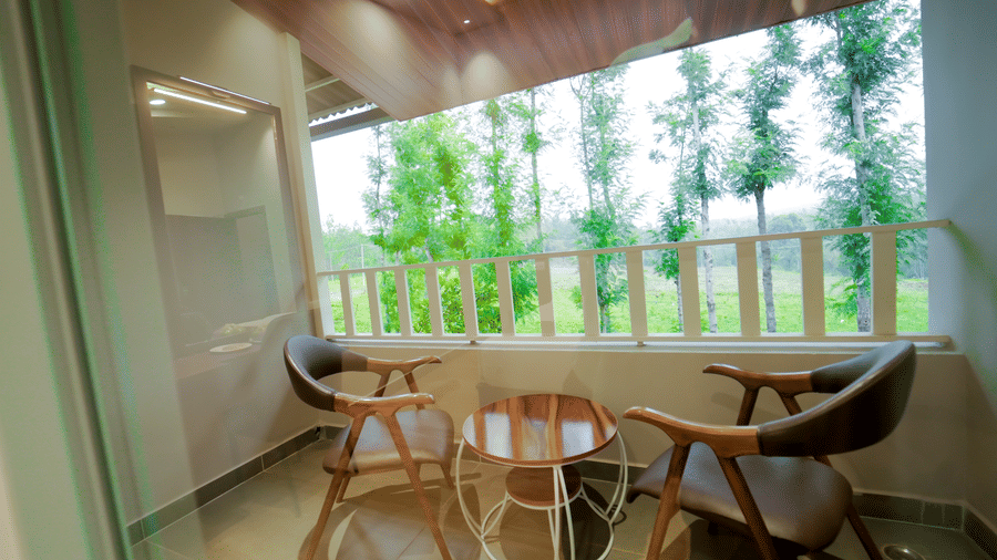 A balcony with two wooden armchairs and a small table at Bindiga Peak Resort.