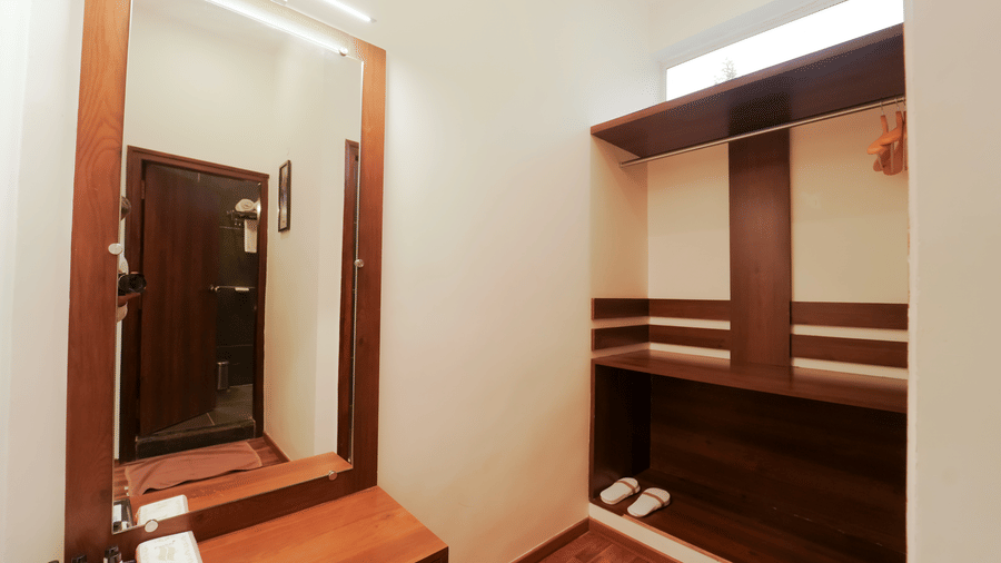 A dressing space featuring a wall mirror with a wooden counter and an open built-in wooden closet unit at Bindiga Peak Resort.