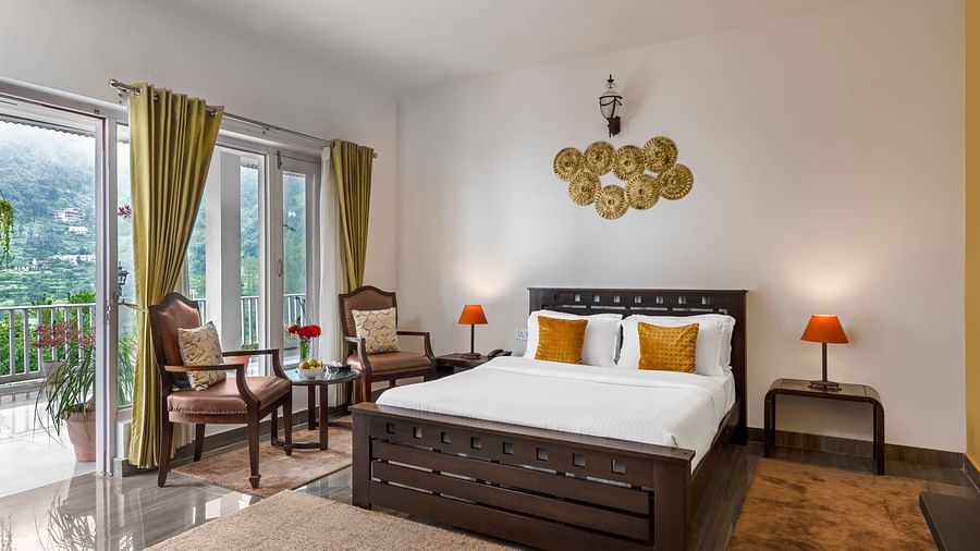 Spacious bedroom with large bed, seating area, and balcony access, at BluSalzz Collection - Suvaasa Resort, Ramgarh.