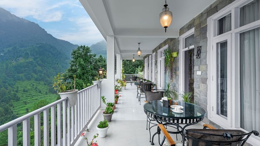 Long verandah with seating arrangements offering panoramic views of the mountains at BluSalzz Collection - Suvaasa Resort, Ramgarh.