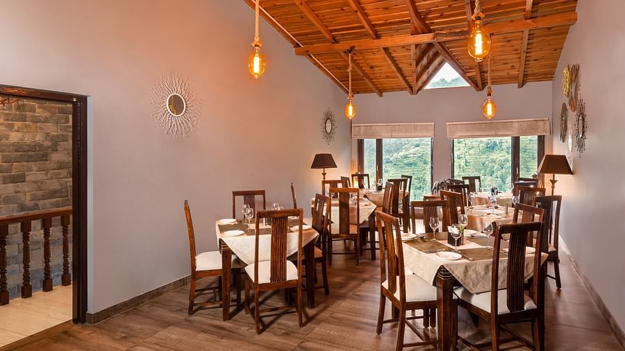 Rustic indoor dining area with wooden furniture and sloped ceiling, at BluSalzz Collection - Suvaasa Resort, Ramgarh.