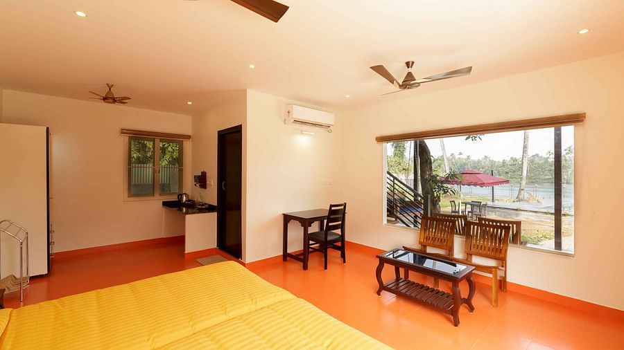 A bedroom with a bed, a seating area by a window, and ceiling fans.