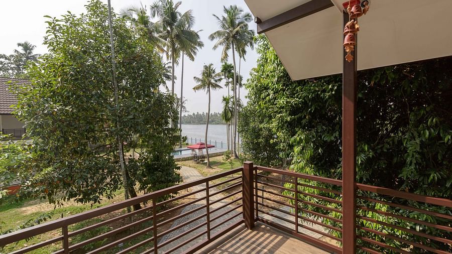 A balcony with a railing overlooking a body of water and palm trees.