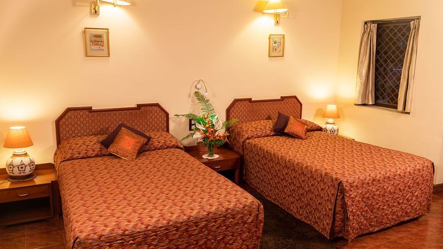 Cosy bedroom with twin beds, warm lighting, and simple decor on the walls - BluSalzz Collection - Tranquil Resort, Wayanad