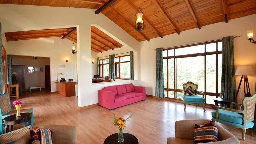 a lobby with, a wall-to-floor window, a teapoy, a pink sofa, wooden flooring, and teal coloured chairs - BluSalzz Escapade - Anant Rasa Resort