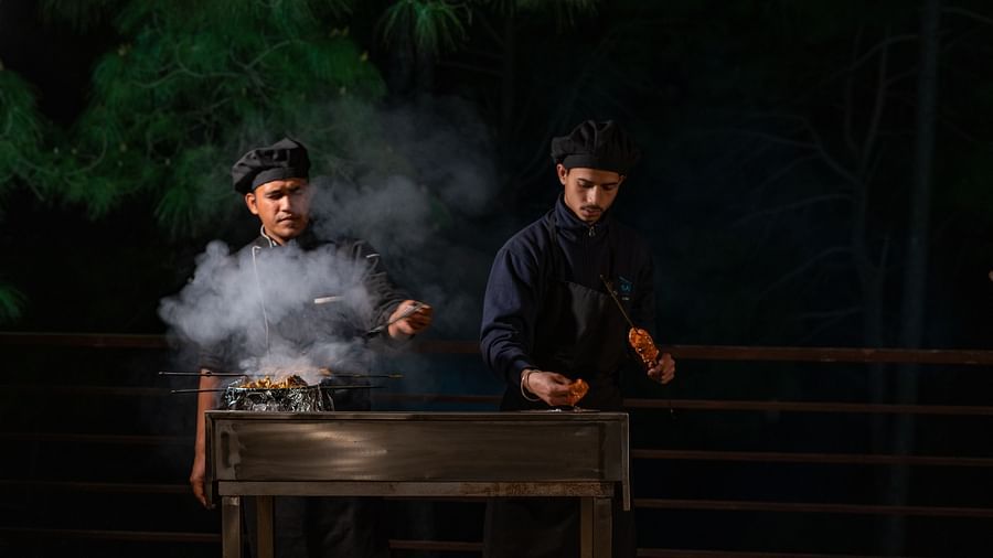 Two chefs preparing barbecues with smoke rising from the sizzling grills at BluSalzz Escapade Resort, Lansdowne