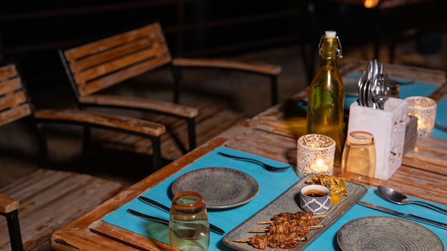 An outdoor dining area in the evening with a table set with food, drinks, and cutlery at BluSalzz Escapade Resort, Lansdowne