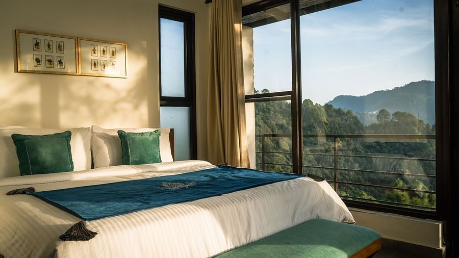 A bedroom with a balcony offering a mountain view and sunlight streaming in at BluSalzz Escapade Resort, Lansdowne