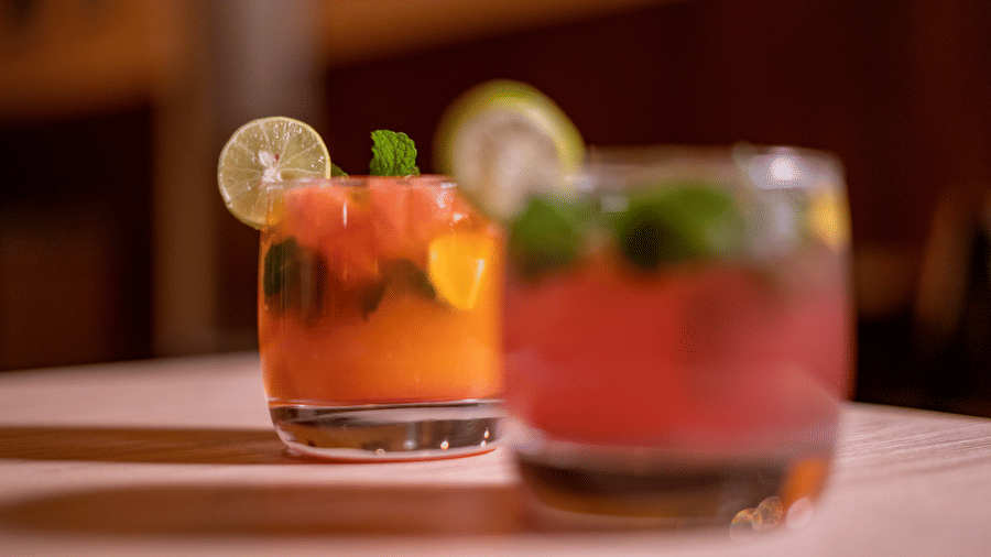 Two glasses containing beverages garnished with fruit slices and mint leaves sit on a surface at a Cafe in BluSalzz Escapade Resort, Lansdowne.