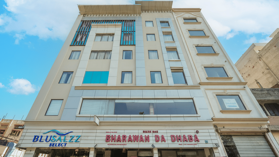 A low-angle exterior shot of a multi-storey hotel building, featuring commercial signage on the ground floor at BluSalzz Select City Centre, Amritsar.