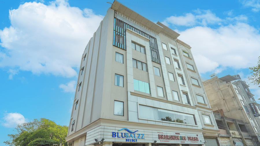 A slightly distant view of a modern hotel building under a blue, cloudy sky, highlighting the clean, vertical facade and large windows at BluSalzz Select City Centre, Amritsar.