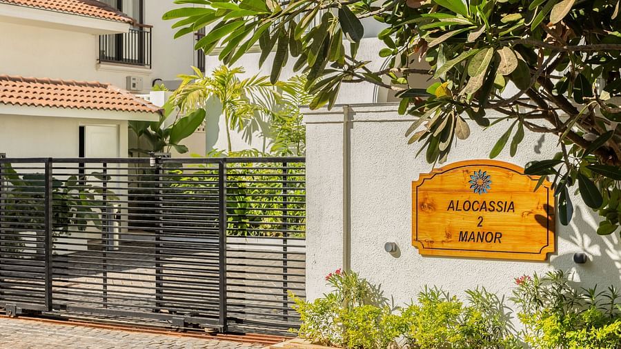 The front view of a luxury villa, showcasing a gated entrance, lush greenery, and a signboard with the property name - BluSalzz Villas - Alocassia, Anjuna