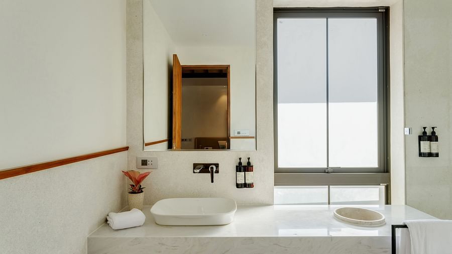 A bathroom with double sinks, a large mirror, and natural light streaming in through a window for an airy atmosphere - BluSalzz Villas - Alocassia, Anjuna