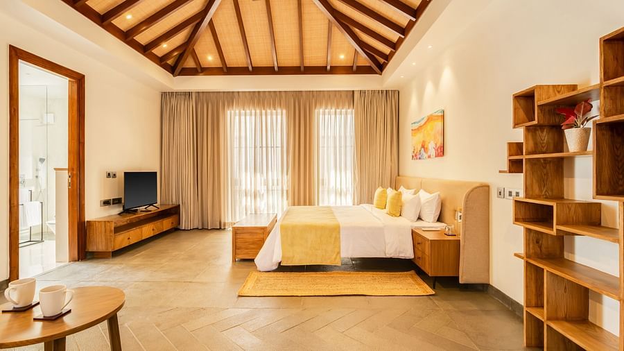 A luxurious bedroom showcasing a warm wooden ceiling, a comfortable bed, and modern furnishings with ample natural light - BluSalzz Villas - Alocassia, Anjuna