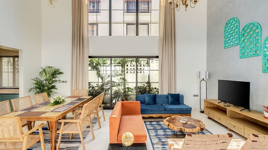 A spacious living and dining room with high ceilings, contemporary furnishings, and large windows flooding the space with natural light - BluSalzz Villas - Alocassia, Anjuna