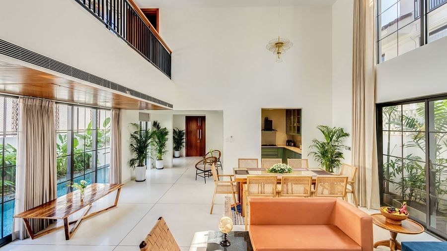 A luxurious open-plan area with a dining table, elegant furnishings, and a staircase leading to the upper level - BluSalzz Villas - Alocassia, Anjuna