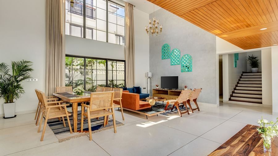 An elegant open-plan living and dining area with high ceilings, modern furniture, and large windows providing natural light - BluSalzz Villas - Alocassia, Anjuna