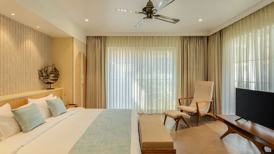 A bright bedroom with a king-sized bed, soft furnishings, and a seating area near large windows - BluSalzz Villas - Alocassia, Anjuna