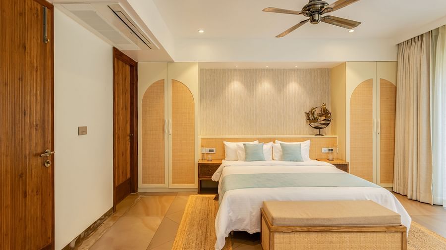 A cosy bedroom with a king-sized bed, wooden accents, and large windows for a bright and inviting atmosphere - BluSalzz Villas - Alocassia, Anjuna