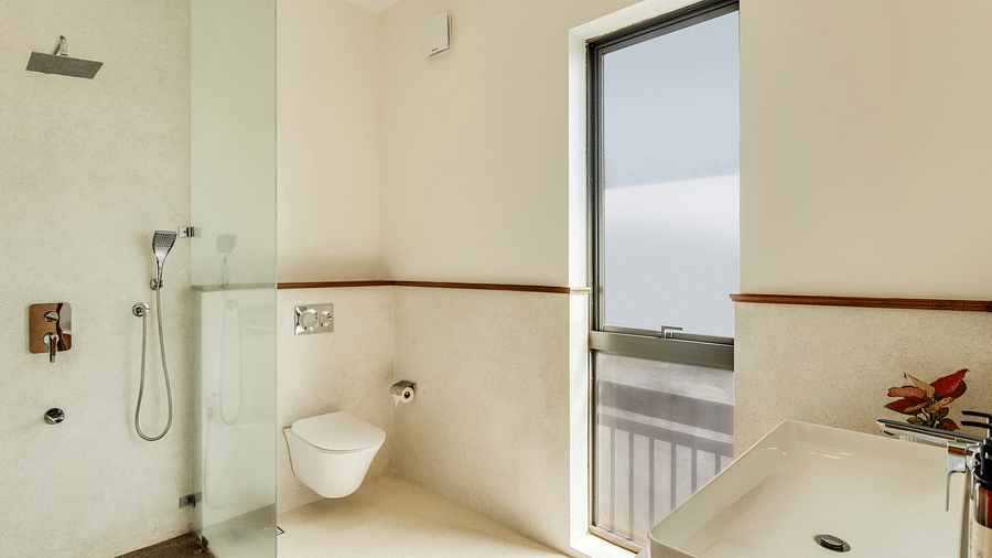 A modern bathroom with a glass-enclosed shower, sleek toilet, and a window offering a view of the outdoors - BluSalzz Villas - Alocassia, Anjuna