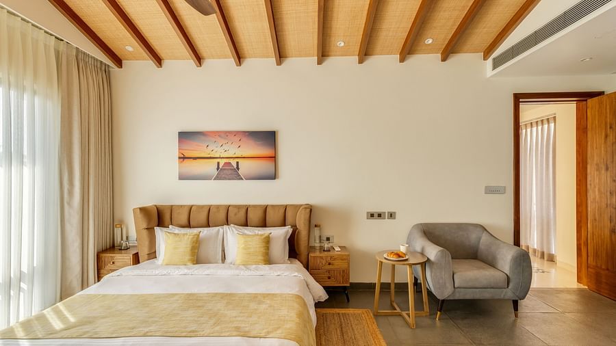 A wide-angle view of a bedroom showcasing a double bed, a work desk, and a doorway leading to a private outdoor area - BluSalzz Villas - Alocassia, Anjuna