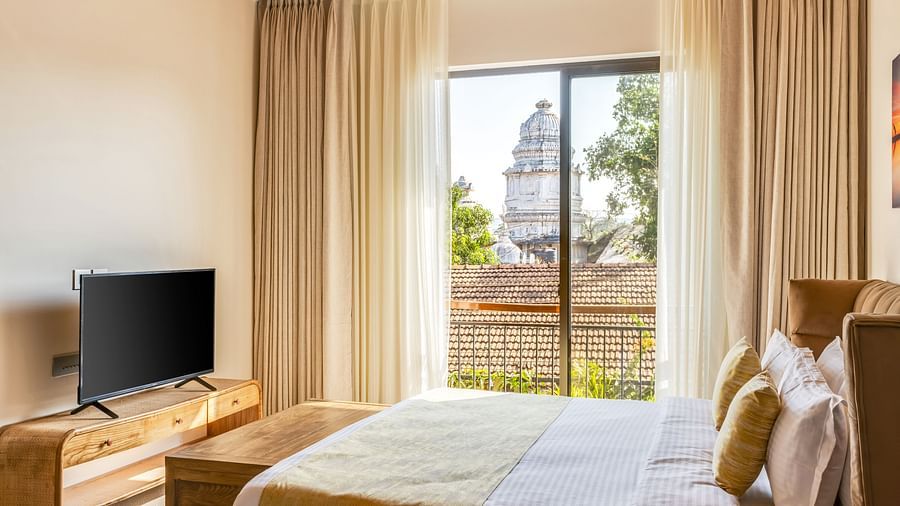A contemporary bedroom with a comfortable king-sized bed, a television, and a door leading to a corridor - BluSalzz Villas - Alocassia, Anjuna