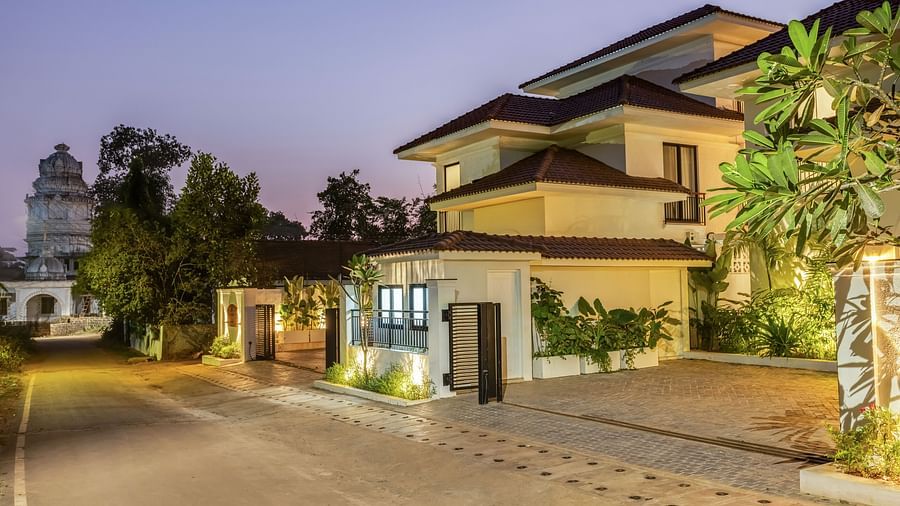 A luxury villa exterior at twilight, showcasing elegant design, a landscaped garden, and a private driveway - BluSalzz Villas - Alocassia, Anjuna
