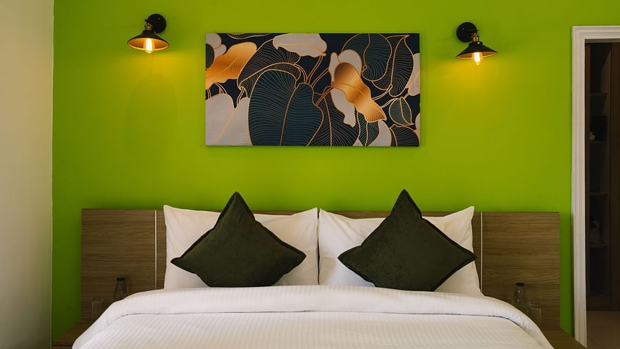 A close-up view of the neatly made bed with a photo frame above the headboard and two light lamps on either side at BluSalzz Villas - The Green Roof, Bhimtal.