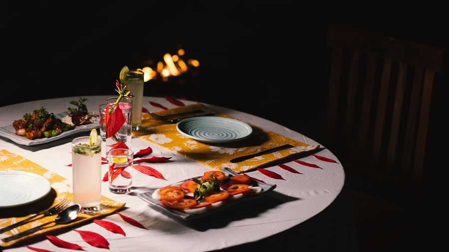 A fully set dinner table at BluSalzz Villas - The Green Roof, Bhimtal, with a cosy campfire glowing in the background.