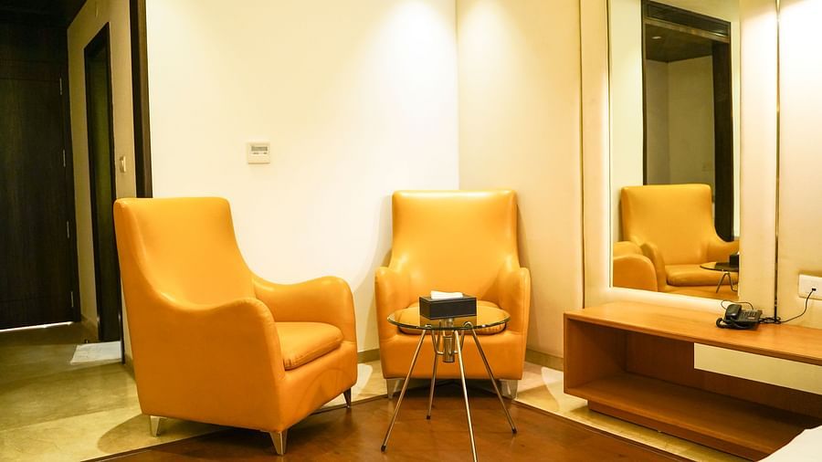  A cosy and inviting lounge area within BNGV Grandeur Hotel and Banquets, showcasing two comfortable orange armchairs and a small table, ideal for relaxation.