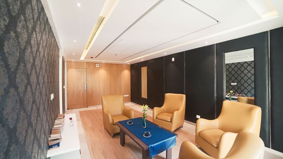 A spacious and inviting lounge area at BNGV Grandeur Hotel and Banquets, with light-colored upholstered chairs, a coffee table, and warm lighting.