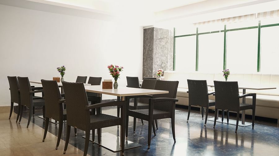 A clean and modern dining room at BNGV Grandeur Hotel and Banquets, furnished with multiple square tables and dark chairs, ready for guests.